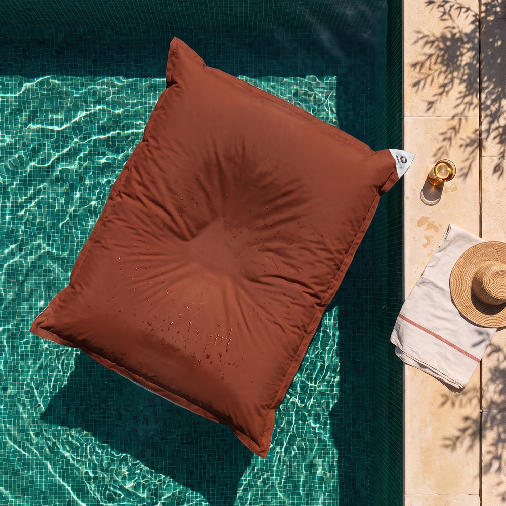 Puf gigante flotante Terracota sobre el agua de una piscina, vista cenital