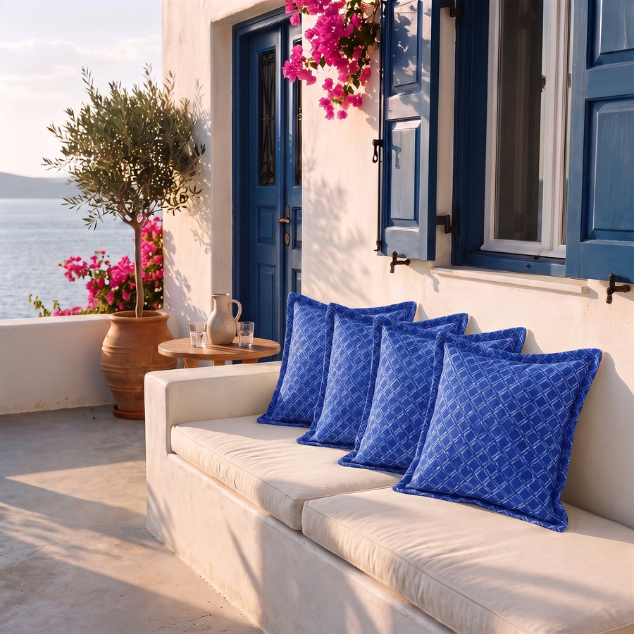 Lote de 4 cojines decorativos 45x45 motivo Náutico Azul en un banco de terraza frente al mar