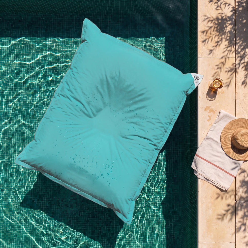 Solo funda, para rellenar – Puf gigante flotante Azul Caribe sobre el agua de una piscina, vista cenital