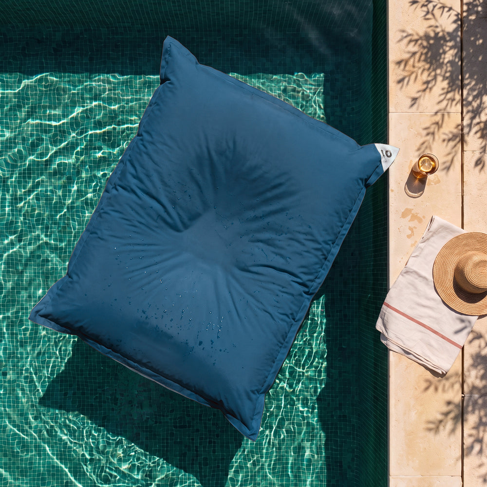 Solo funda, para rellenar – Puf gigante flotante Azul Petróleo sobre el agua de una piscina, vista cenital