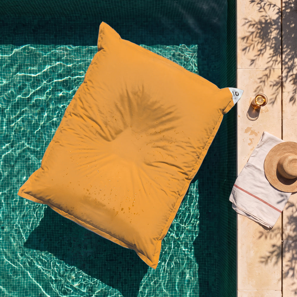 Solo funda, para rellenar – Puf gigante flotante Amarillo Miel sobre el agua de una piscina, vista cenital